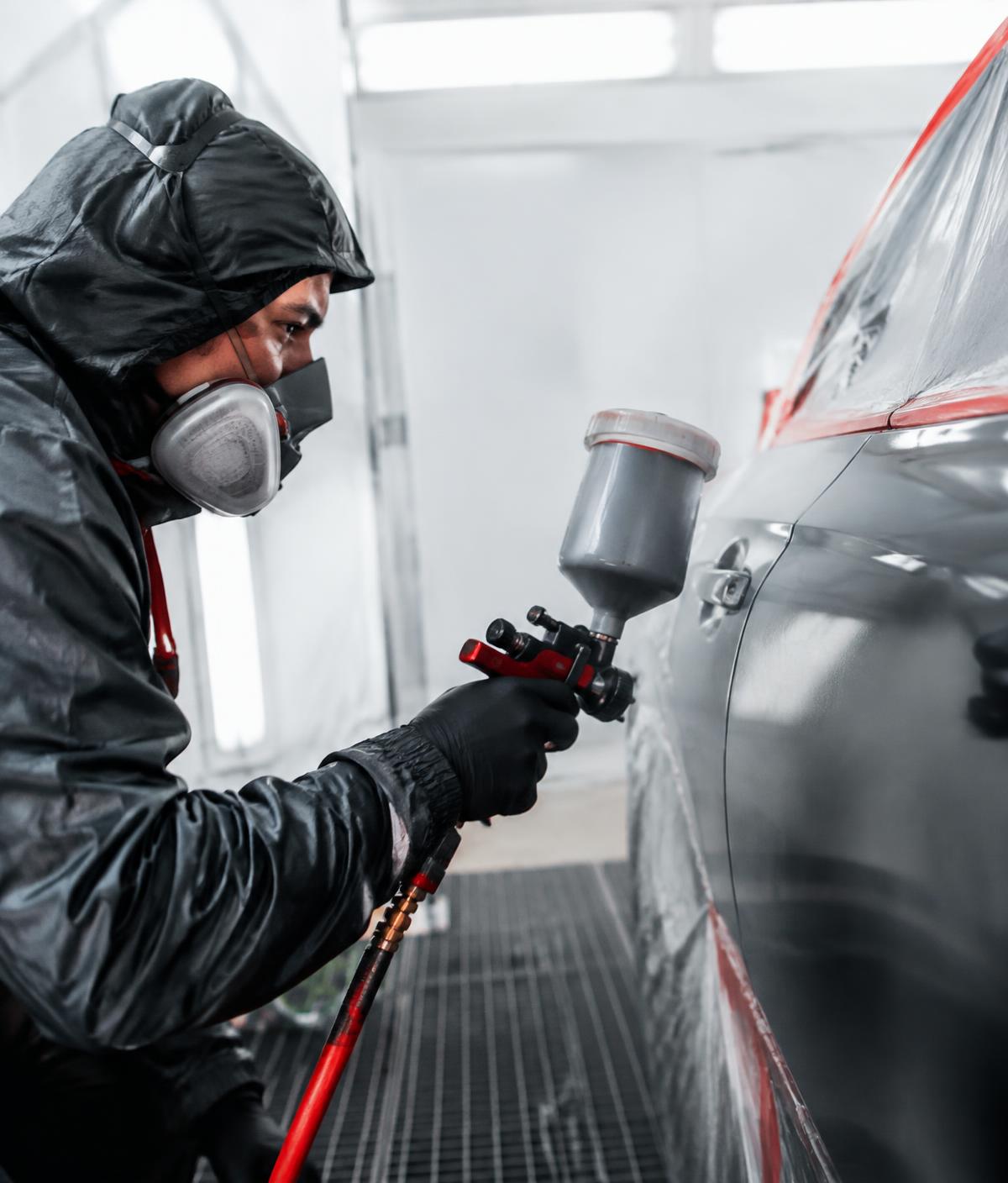 Technician spray painting a car door